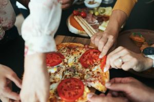 ludzie sięgający po pizzę